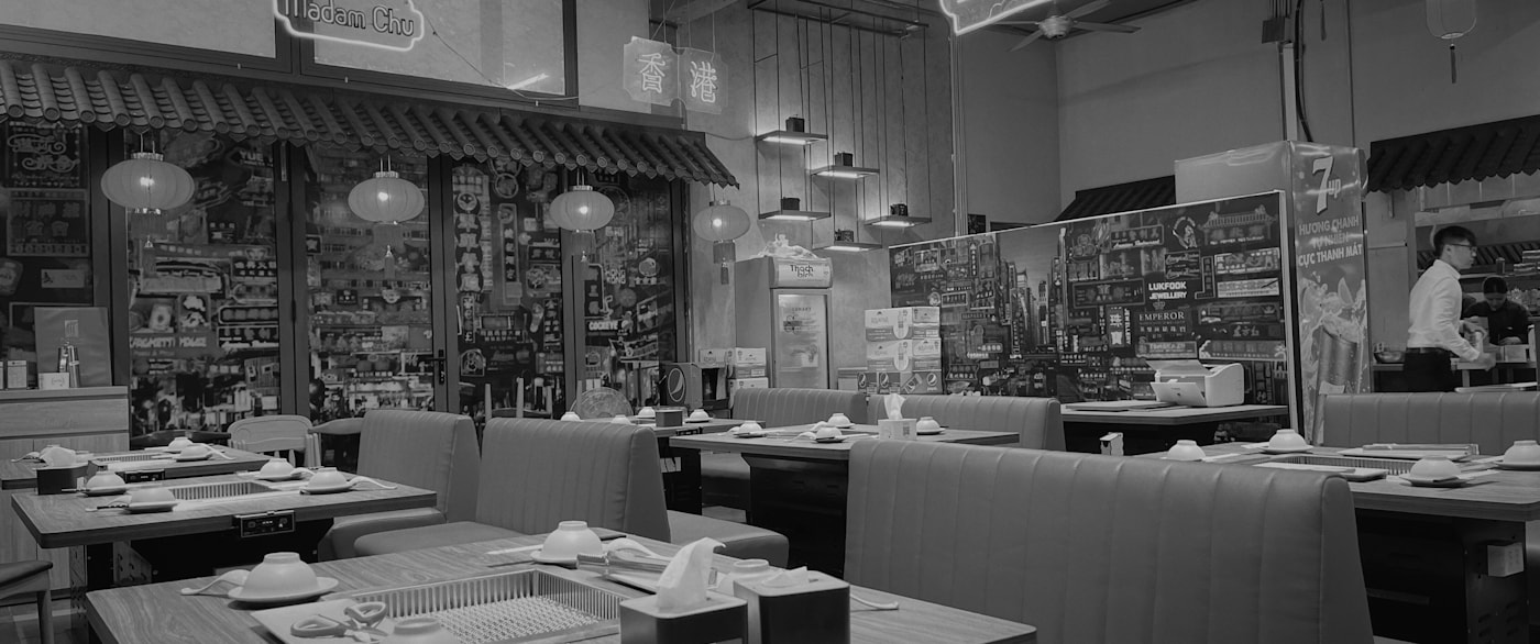 A monochrome restaurant interior with tables and pendant lights