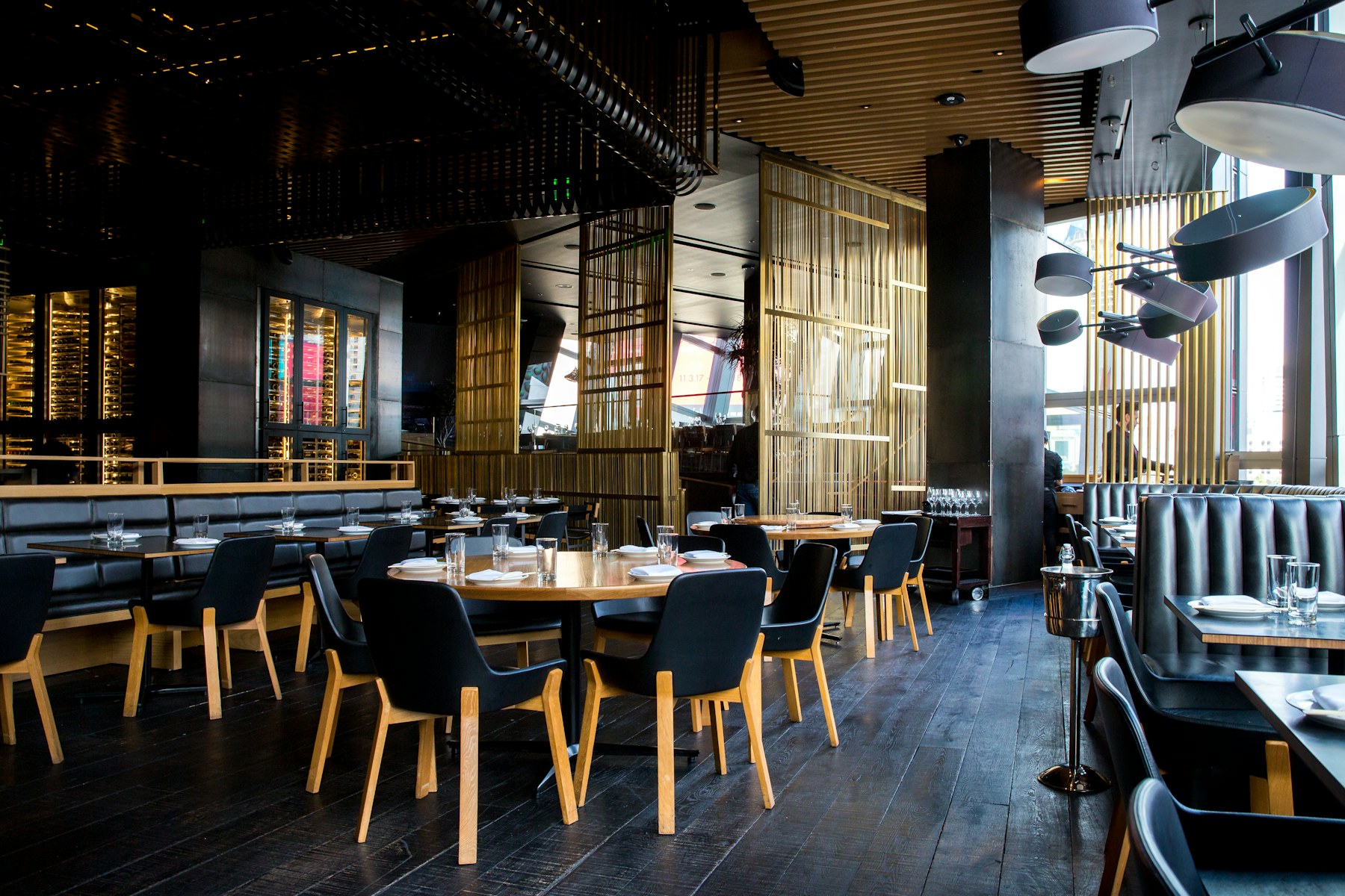 A modern restaurant dining room with dark finishes and sculptural lighting